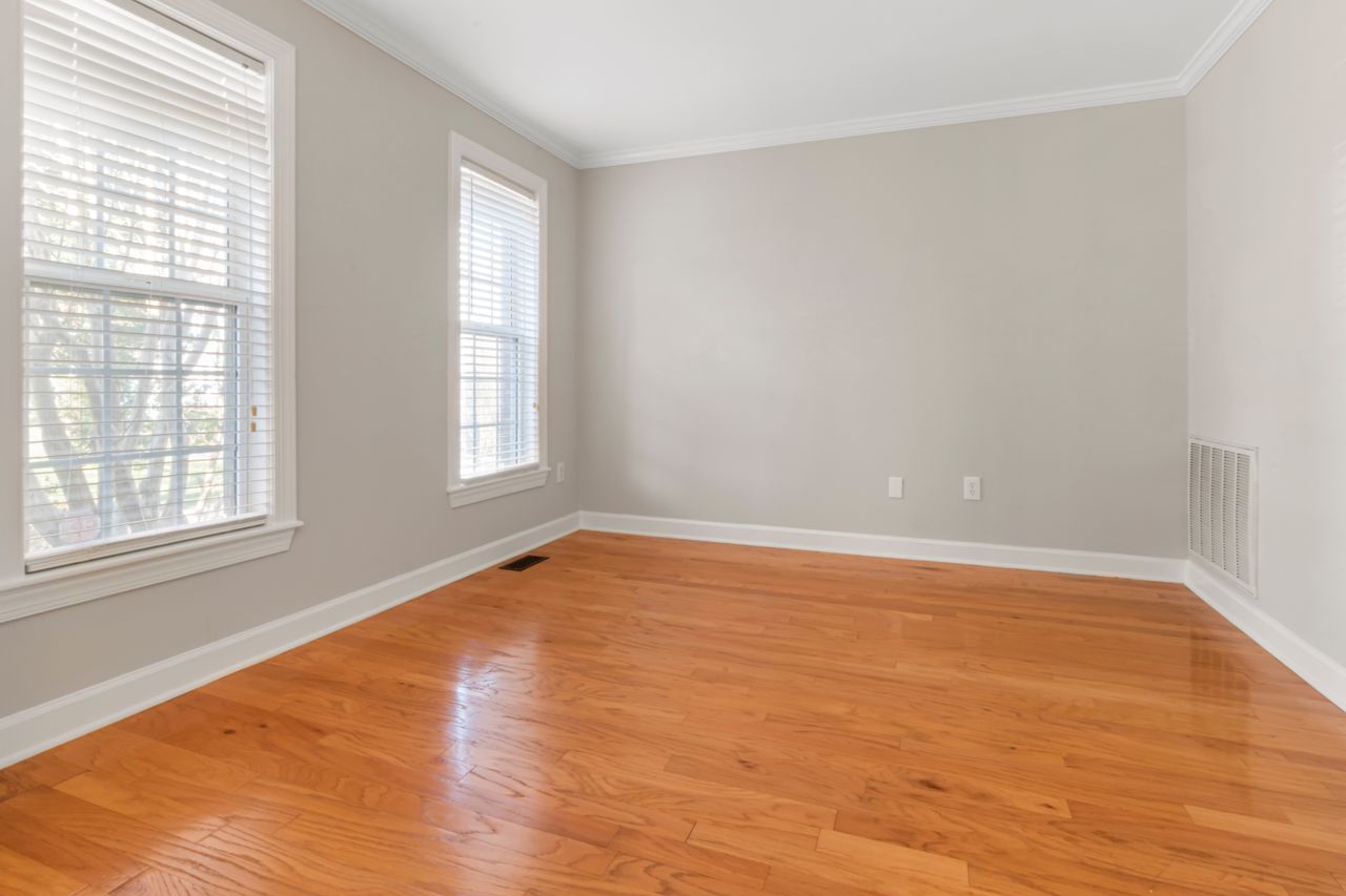 Spacious empty room with natural light, hardwood floors, and neutral walls.